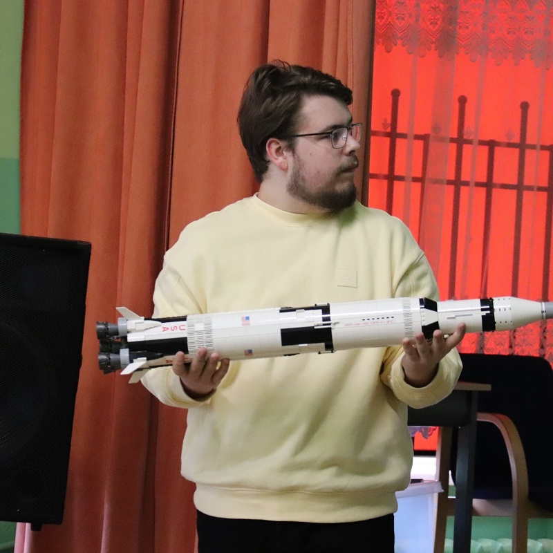 prezenter pokazuje model Saturna V z klocków Lego