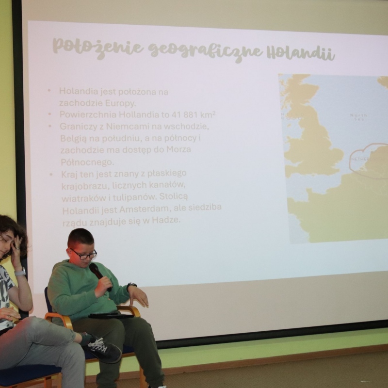 Dwóch uczniów siedzi w tle wyświetlony slajd położenie geograficzne Holandii