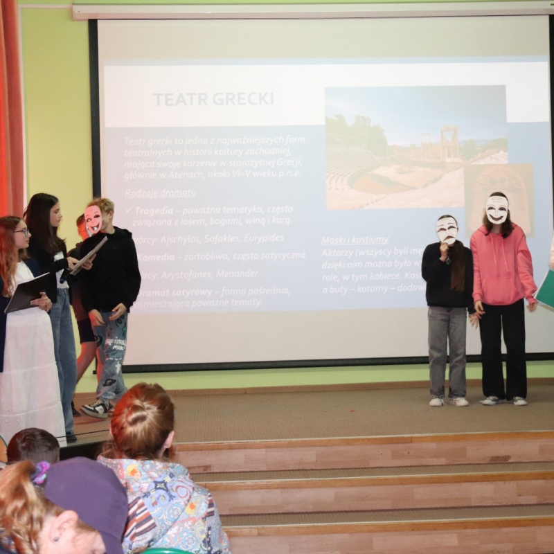 Na scenie uczniowie w tle slajd teatr grecki i dwójka uczniów w maskach