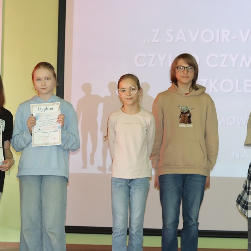 5 uczniów stoi na scenie