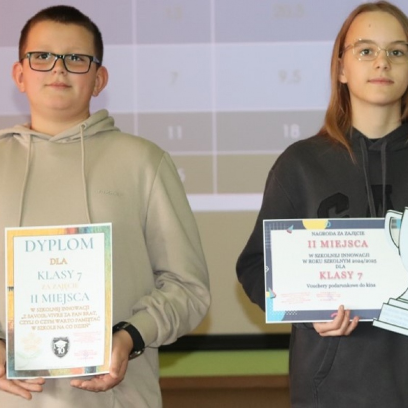 Uczeń i uczennica z klasy 7 z dyplomami, papierowym pucharem i nagrodą