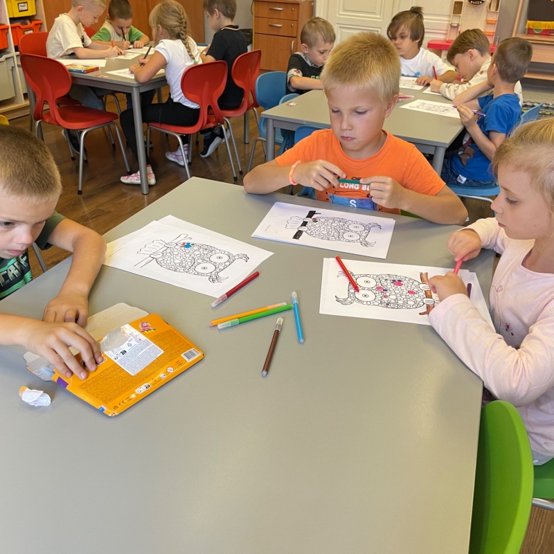 Uczniowie przy stolikach malują