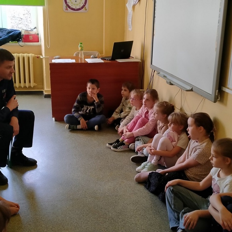 Uczniowie słuchają jak pan policjant opowiada