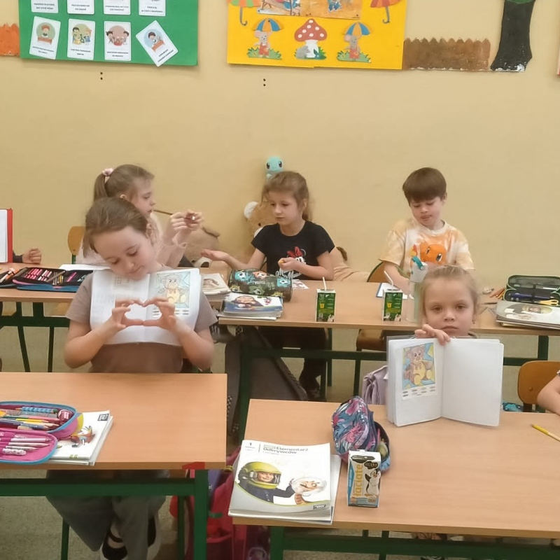 Uczniowie klasy 1b z zeszytami i zadaniem pokoloruj wg numerków