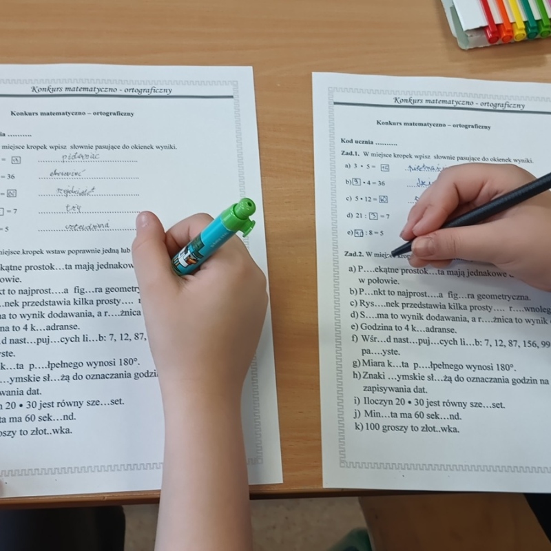 uczennice rozwiązują karty pracy, widoczne tylko ręce
