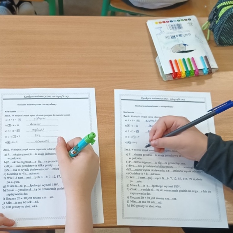uczennice rozwiązują karty pracy, widoczne tylko ręce