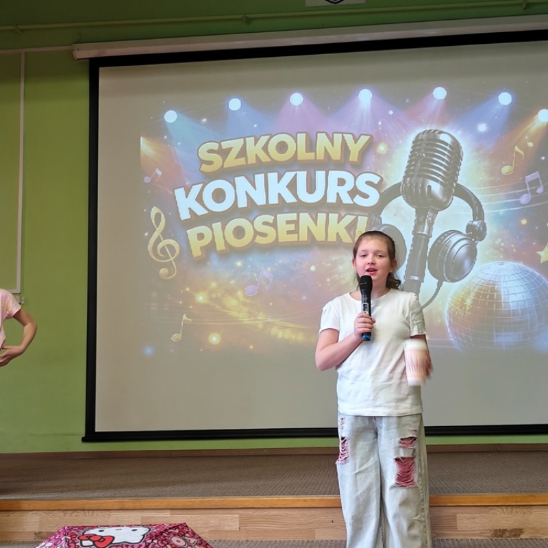 dziecko śpiewające na tle baneru szkolny konkurs piosenki