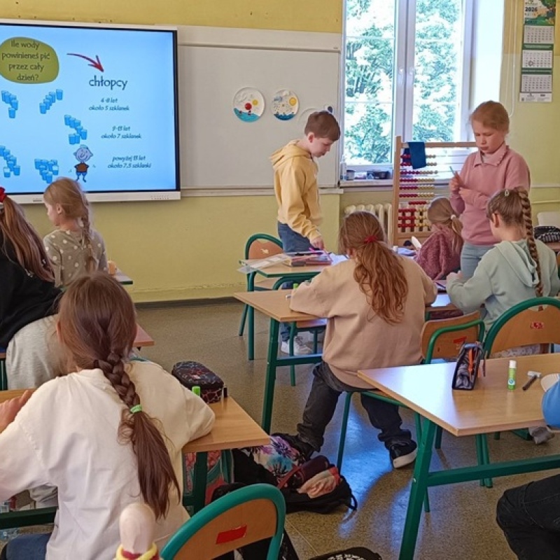 uczniowie w ławkach tworzą pracę plastyczną na papierowych tackach