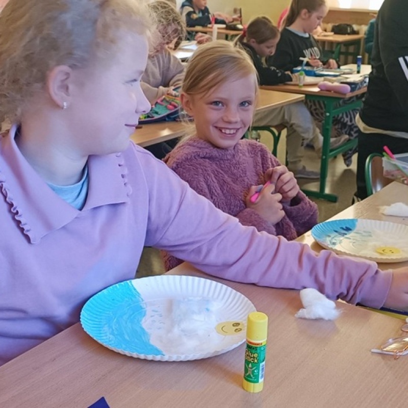 uczniowie w ławkach tworzą pracę plastyczną na papierowych tackach