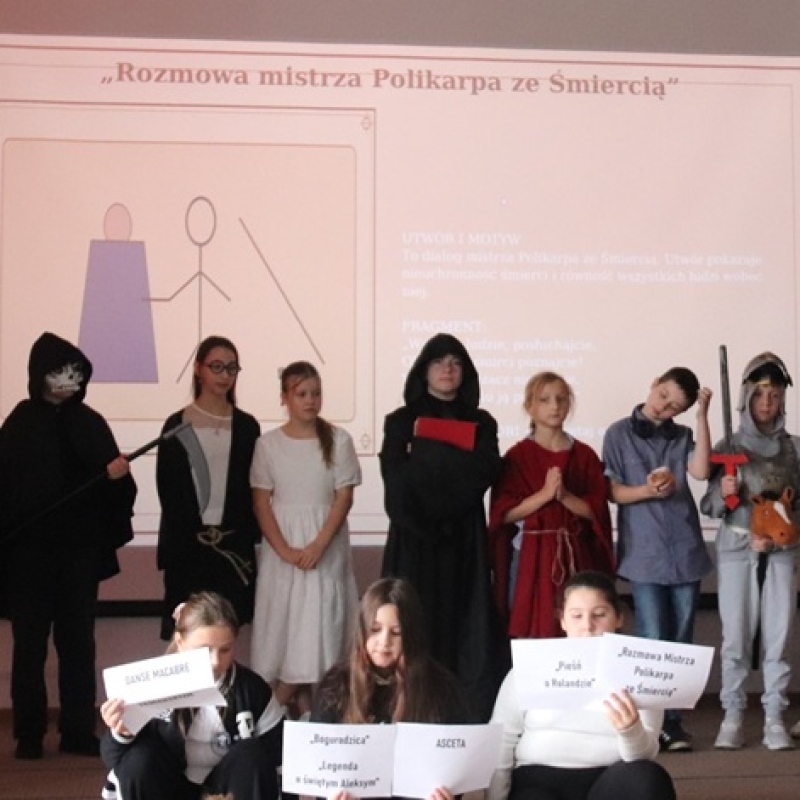 uczniowie na scenie w strojach zakonnika, rycerza, śmierci