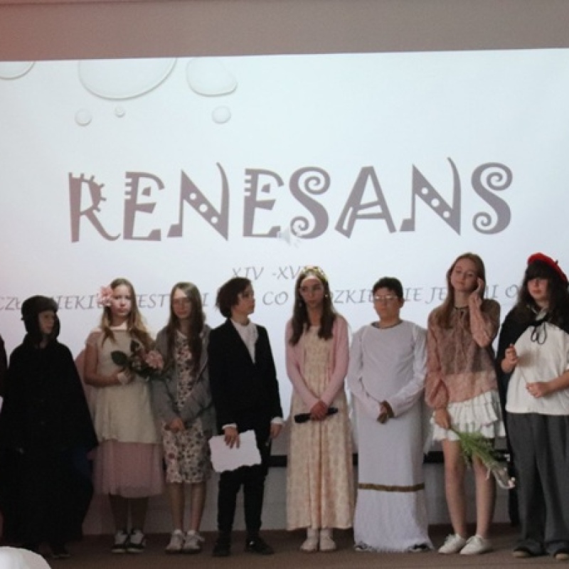 uczniowie na scenie na tle napisu renesans w strojach odzwierciedlających epokę