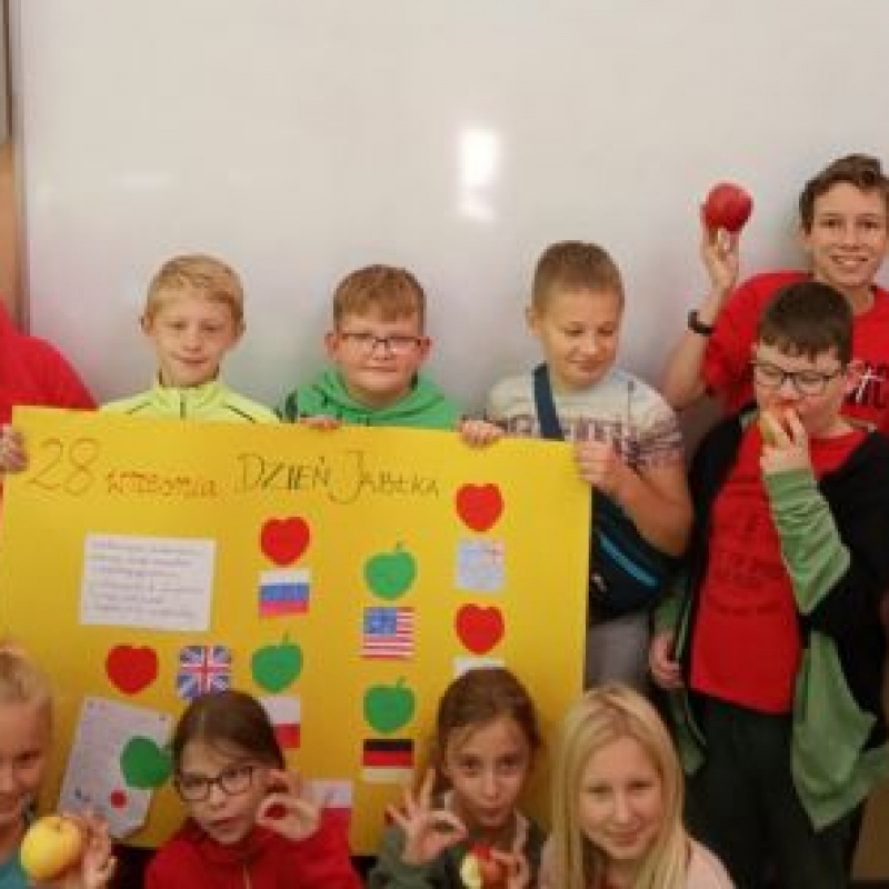 dzieci trzymające w ręku jabłka i plakat o jabłkach
