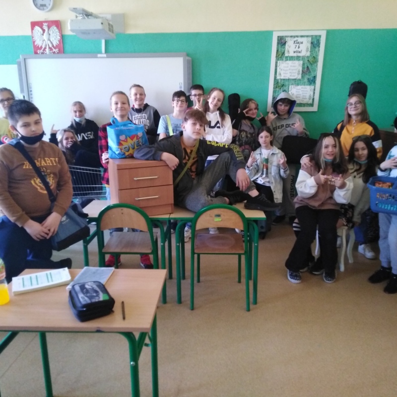 zdjecie:Uczniowie klasy 7b z przedmiotami, w których przynieśli przybory szkolne zamiast plecaków