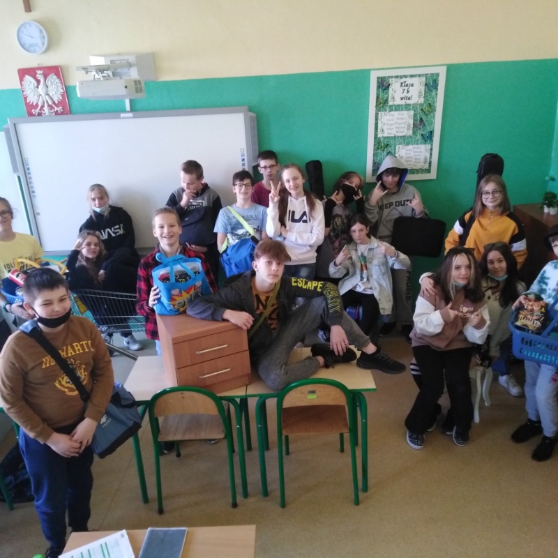 zdjecie:Uczniowie klasy 7b z przedmiotami, w których przynieśli przybory szkolne zamiast plecaków