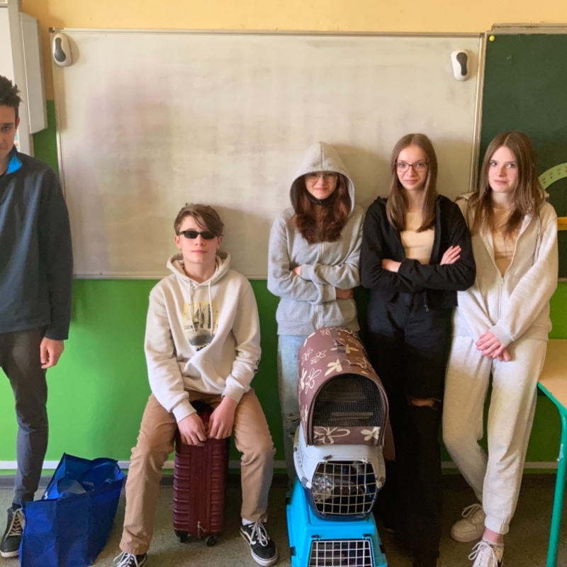 zdjecie:Uczniowie klasy 8b z przedmiotami, w których przynieśli przybory szkolne zamiast plecaków